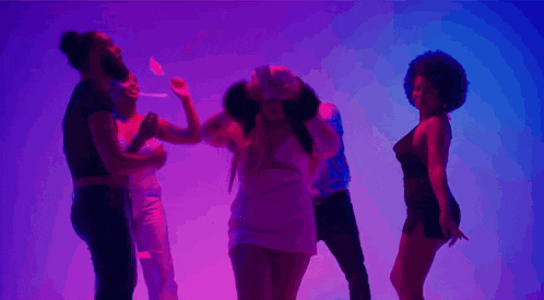 a woman in a pink dress is dancing with a group of people in purple lights .