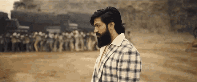 a man with a beard wearing a plaid suit stands in front of a crowd of people