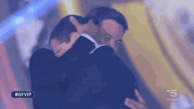 two men in suits are hugging each other in a blurry photo .