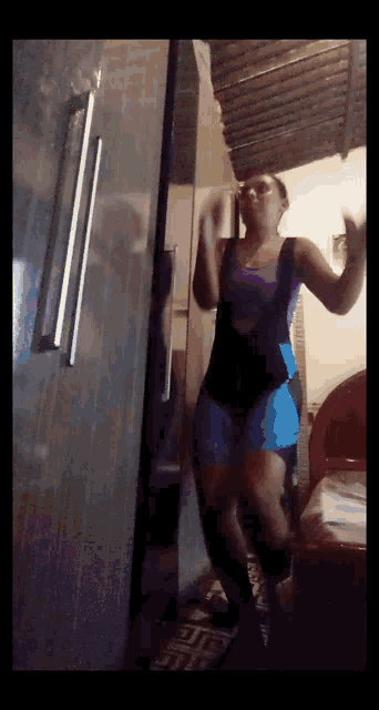 a woman in overalls is dancing in front of a fridge