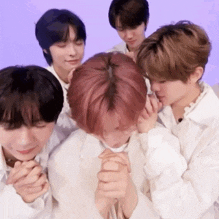 a group of young men are praying together with their hands folded in front of their faces .