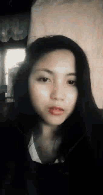 a woman with long black hair is making a funny face while looking at the camera .