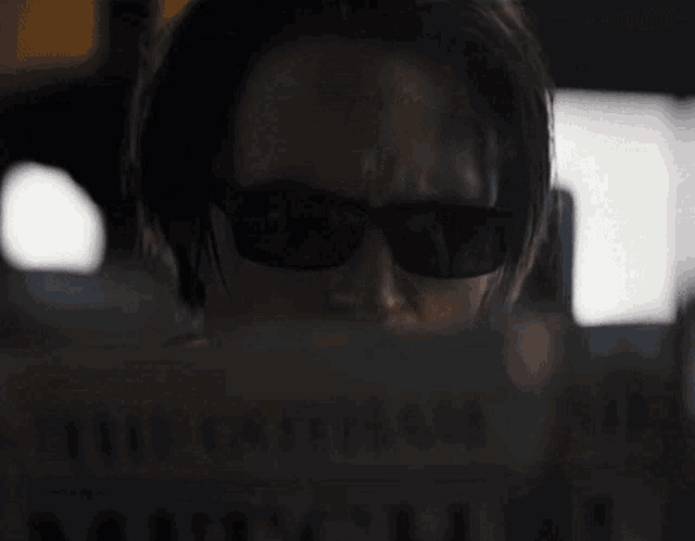 a man wearing sunglasses is reading a newspaper with the headline " the guardian "