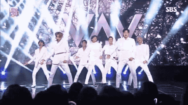 a group of men are dancing on a stage in front of a sbs logo .