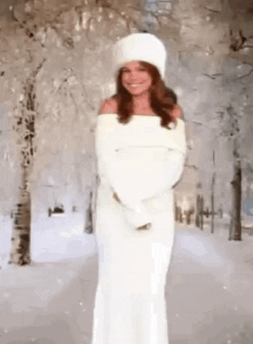 the woman is wearing a white dress and a white hat .
