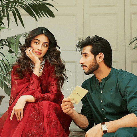 a woman in a red dress sits next to a man in a green outfit