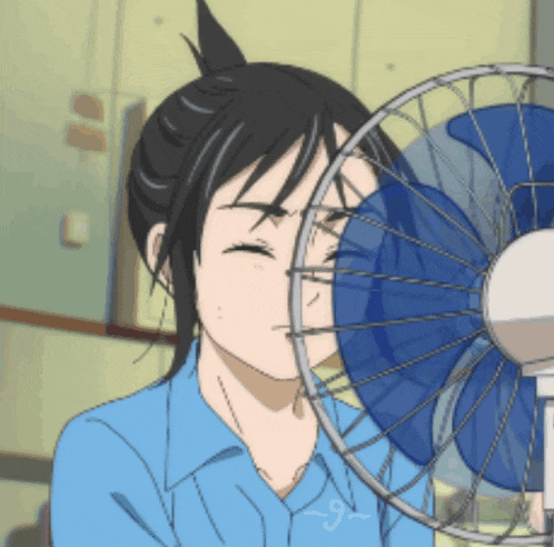 a girl in a blue shirt is blowing a fan