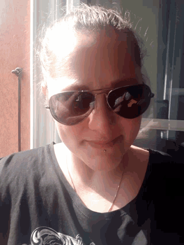 a woman wearing sunglasses and a black shirt smiles for the camera