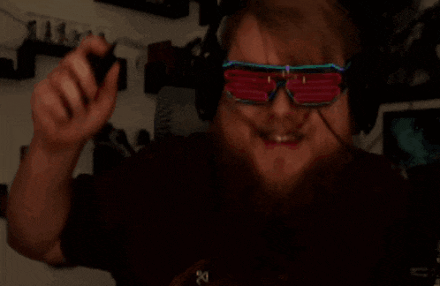 a man wearing headphones and neon sunglasses holds a controller