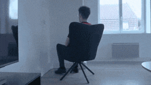 a man is sitting in a chair in front of a window in a living room .