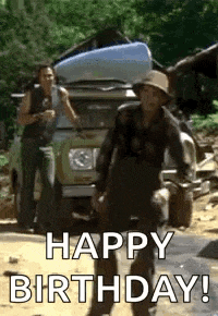 a man in a hat is standing in front of a car and says `` happy birthday '' .