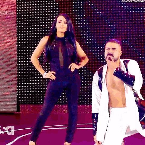 a woman in a black jumpsuit is standing next to a man in a white jacket .
