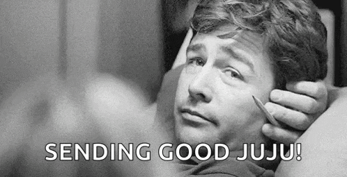 a man is laying on a bed holding a thermometer in his mouth and sending good juju .