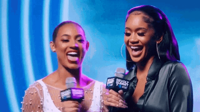 two women holding microphones that say revolt