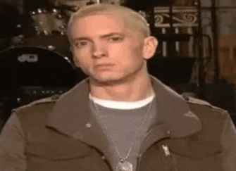 eminem is wearing a jacket and a necklace and making a funny face .