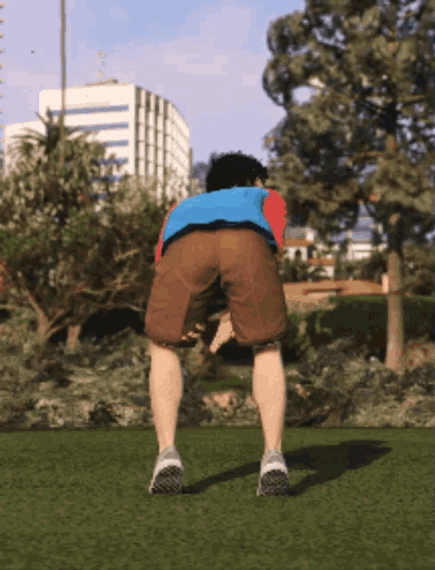 a man in a blue vest and brown shorts is squatting on a grassy field