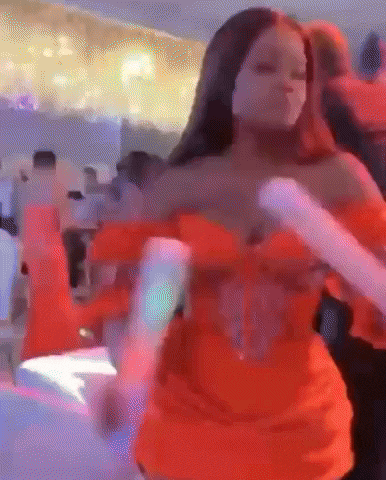 a woman in a red dress is dancing in a room with people .