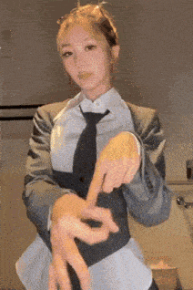 a woman in a suit and tie is making a hand gesture with her fingers .