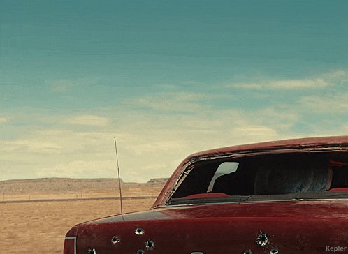 a red car has bullet holes in it and the word kepler is on the bottom right