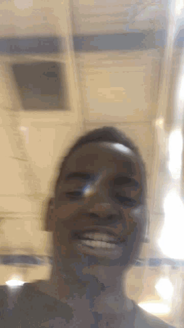 a blurry picture of a man smiling in front of a white ceiling