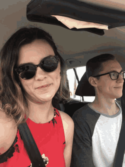 a man and a woman wearing sunglasses are sitting in a car
