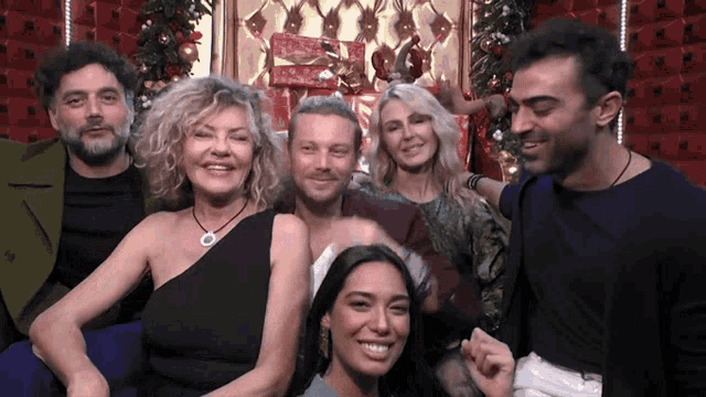 a group of people are posing for a picture in front of a christmas tree