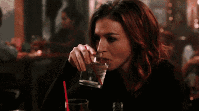 a woman with red hair is holding a drink with a straw