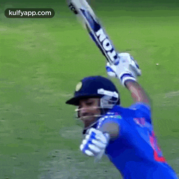 a man in a blue shirt is swinging a bat on a field .