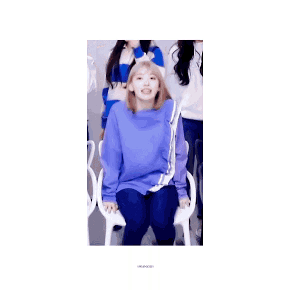 a girl in a purple shirt is sitting in a chair with her hands in the air