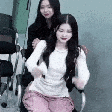 a woman is sitting on a chair next to another woman who is sitting on a chair .