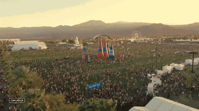 a large crowd at a music festival with a welcome sign in the middle