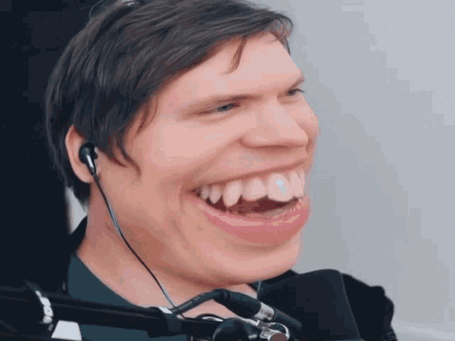 a man wearing ear buds and a microphone is smiling