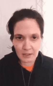 a close up of a woman 's face with a black jacket and a necklace .