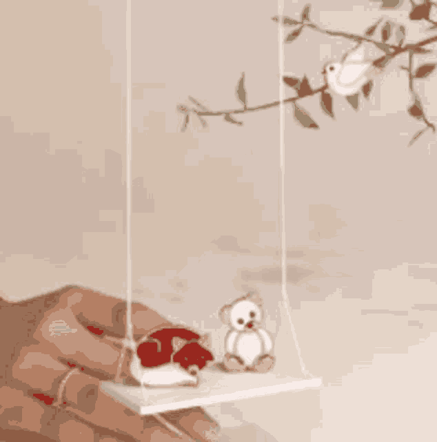 a person is holding a swing with a teddy bear and bird on it