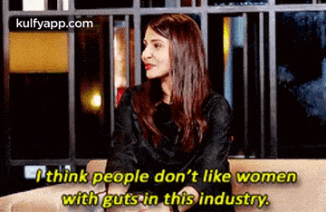 a woman is sitting on a couch and talking to another woman .