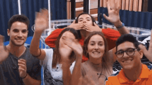 a group of young people are posing for a picture with their hands up in the air .
