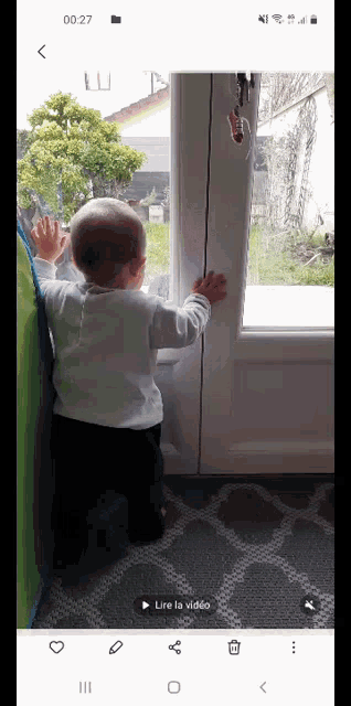 a baby is standing in front of a door and looking out