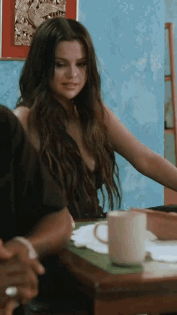 a woman sits at a table with a cup of coffee on it