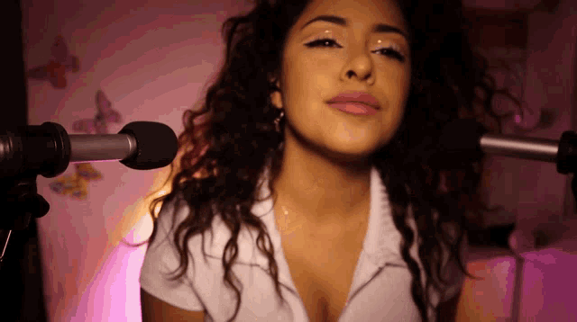 a woman with curly hair is standing in front of a microphone