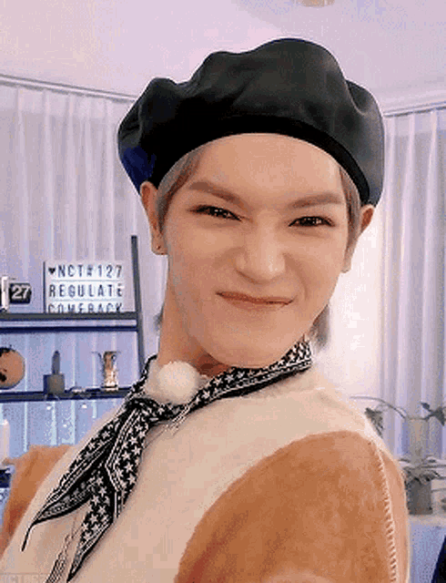 a young man wearing a black beret and a scarf is smiling
