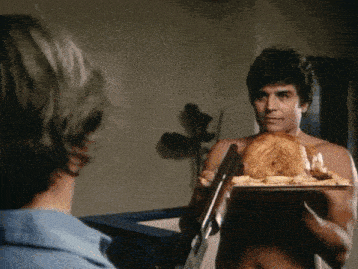 a shirtless man is holding a tray of food and a shotgun