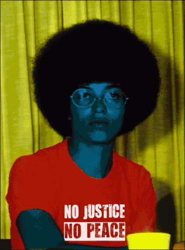 a woman wearing a red shirt that says " no justice no peace "