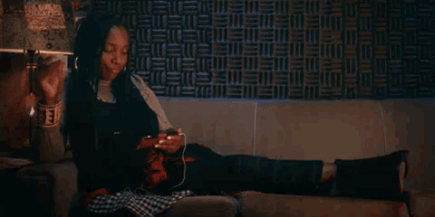a woman is sitting on a couch with her legs crossed and listening to music .