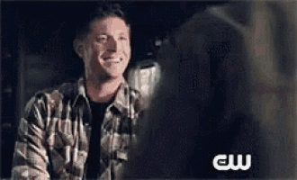 a man in a plaid shirt is smiling at a woman in a black shirt .
