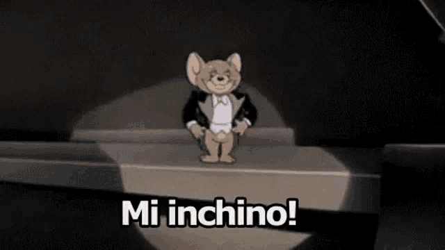 a cartoon mouse in a tuxedo is standing on a stage and says `` mi inchino ! ''
