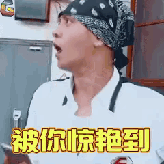a man wearing a bandana is holding a cell phone and making a funny face .