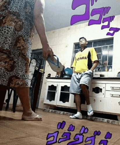 a man wearing a yellow shirt that says itmba stands in a kitchen