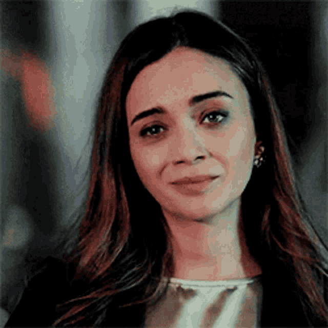 a woman with long dark hair is smiling and looking at the camera