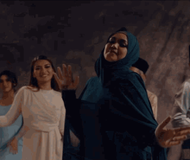 a woman wearing a hijab is dancing with other women