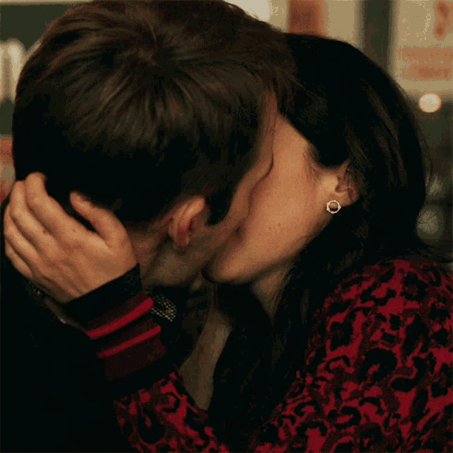 a man and a woman are kissing and the woman is wearing a red and black dress